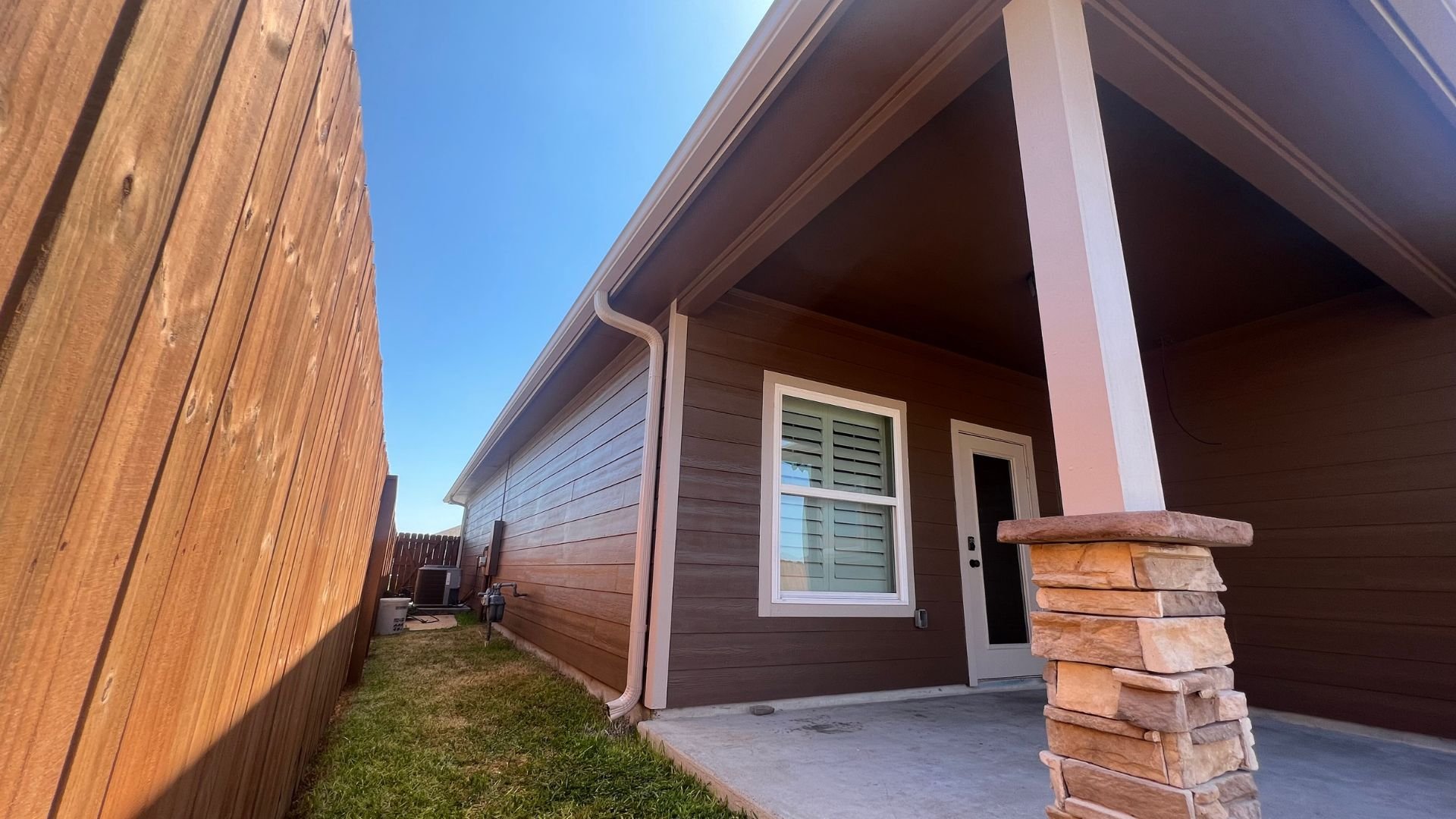 Modern house exterior with stone pillar, wooden siding, and blue sky