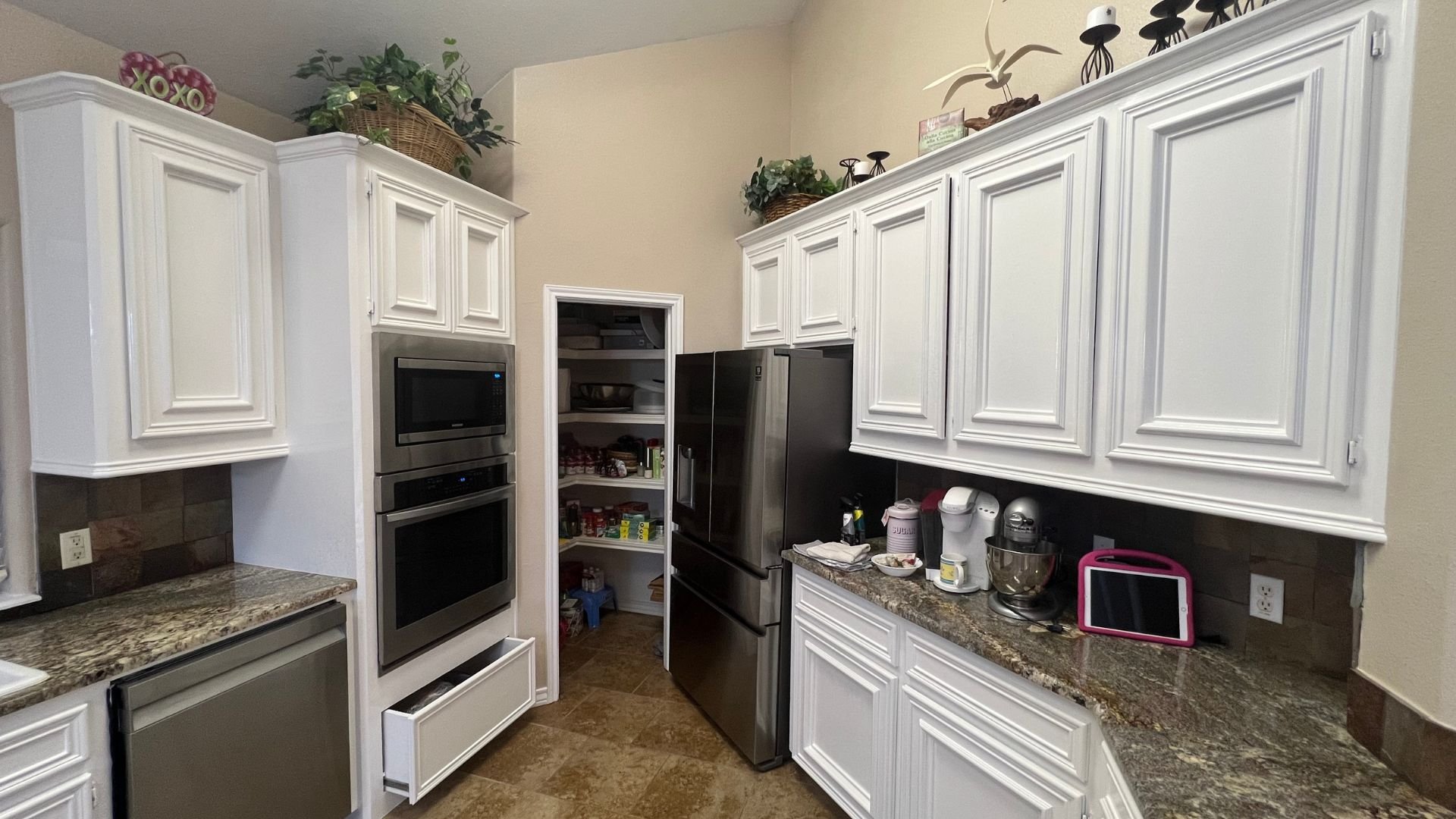 Modern white kitchen with stainless steel appliances and granite countertops