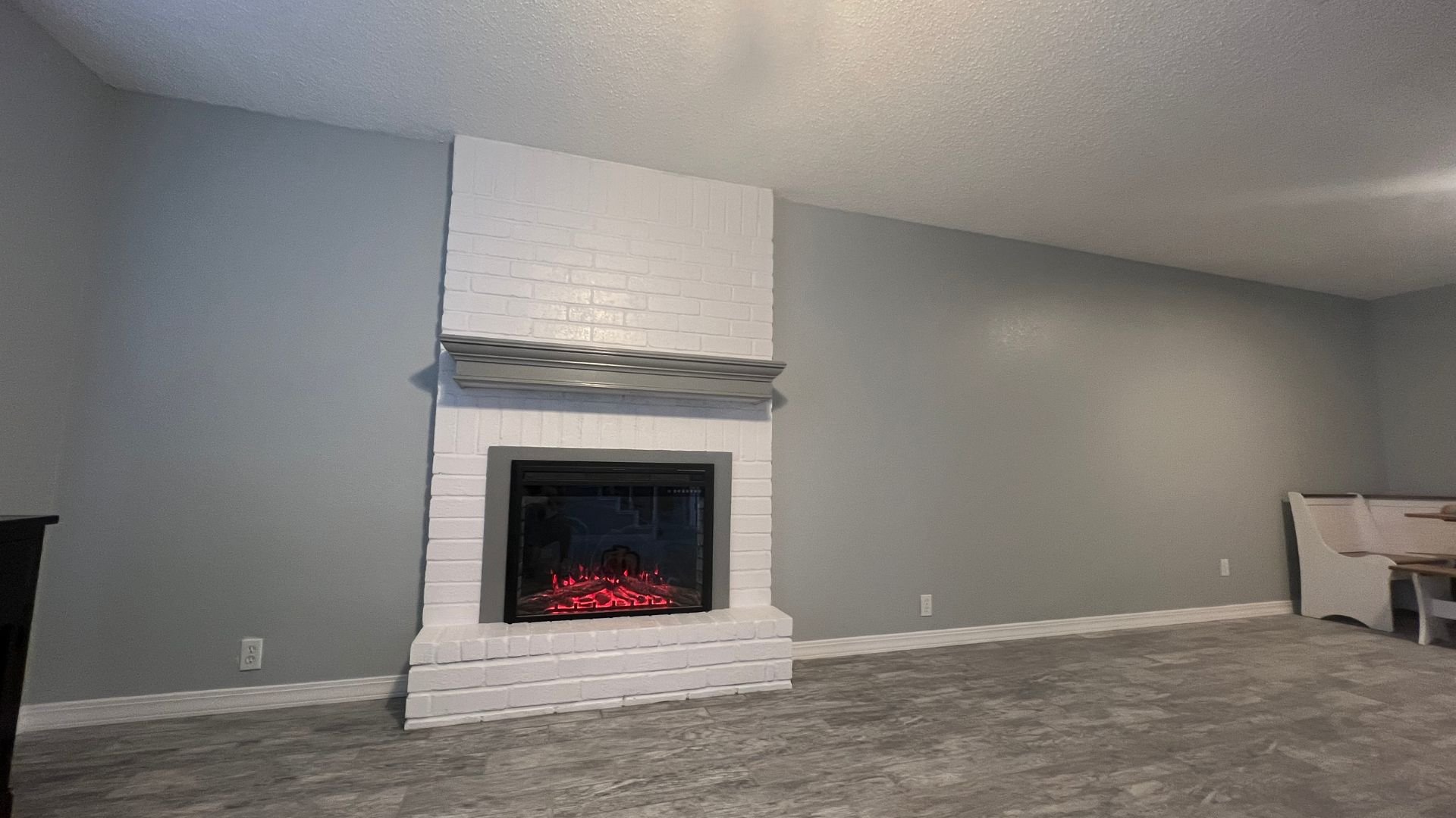 White brick fireplace with glowing red electric insert in gray room