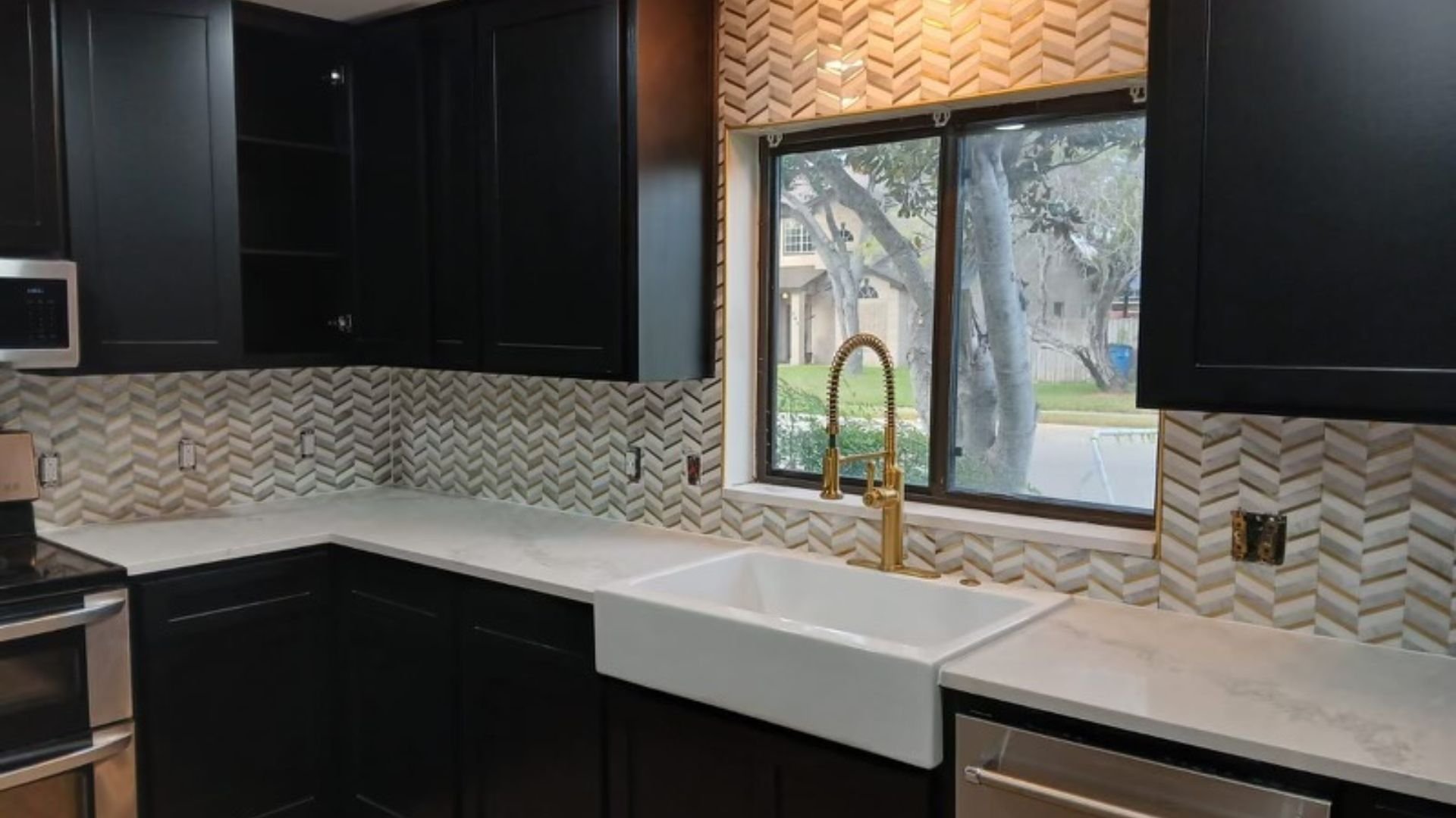 Modern kitchen with black cabinets, white sink, and herringbone backsplash