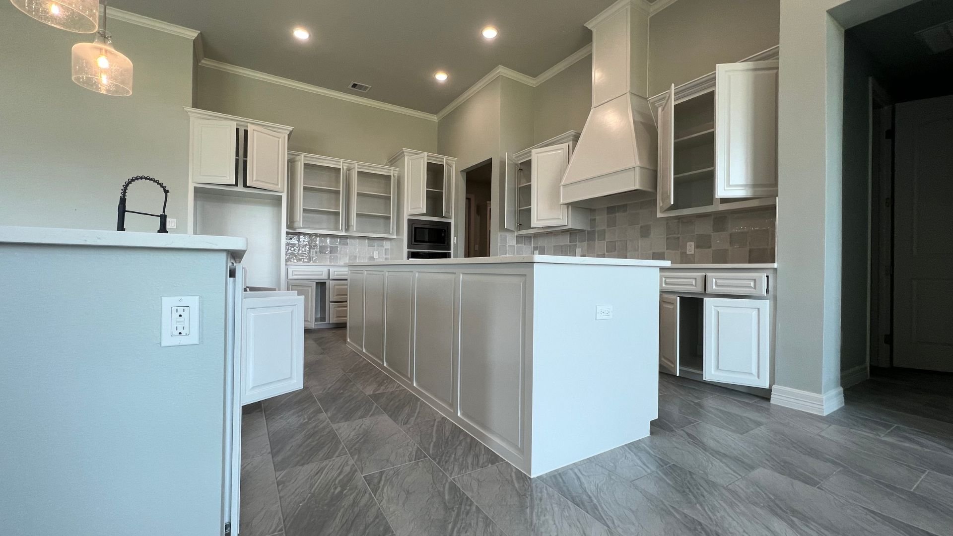 Modern white kitchen with island, pendant lights, and gray tile flooring