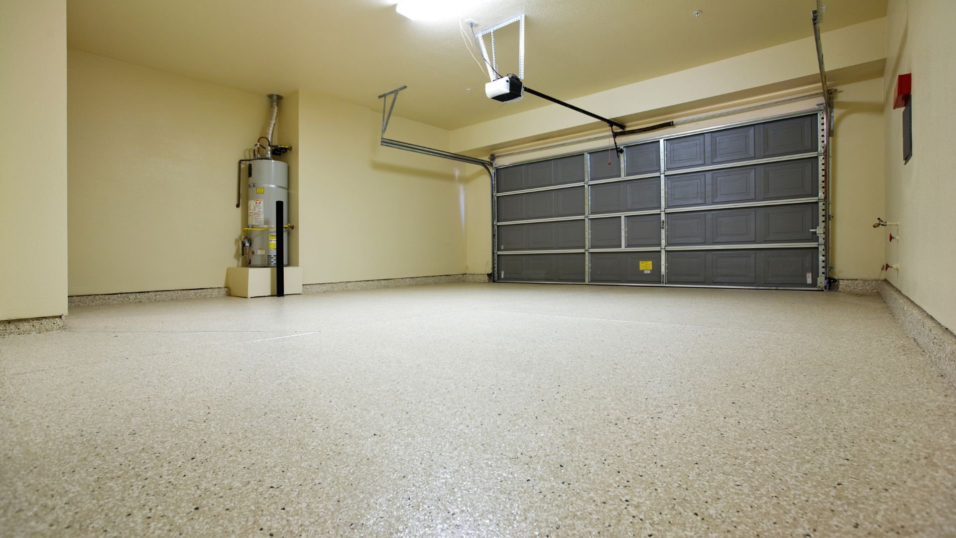 Empty clean garage interior with gray door and water heater