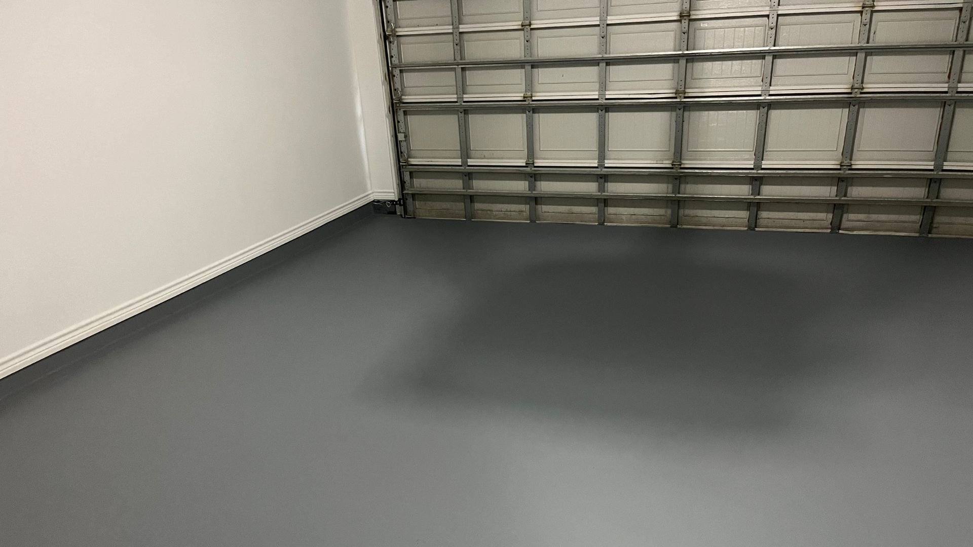 Empty garage interior with gray floor and white walls
