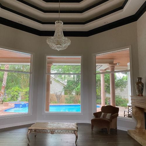 Elegant room with chandelier, large windows overlooking swimming pool and garden